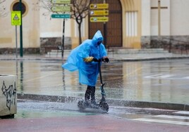 Una persona conduce un patinete bajo la lluvia en Málaga.
