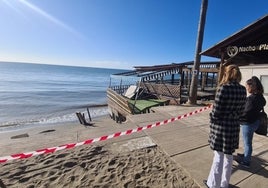 La alcaldesa de Mijas y una familiar del dueño del chiringuito contemplan los daños causados por el temporal.