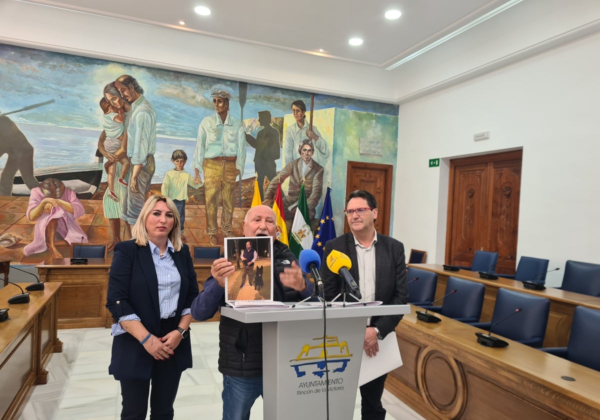 Rocío Calderón, de IU-Con Rincón; José María Gómez, de Por Mi Pueblo, que muestra una foto del primer teniente de alcalde, Borja Ortiz, con el perro policía, y Antonio Sánchez, del PSOE, en la rueda de prensa.