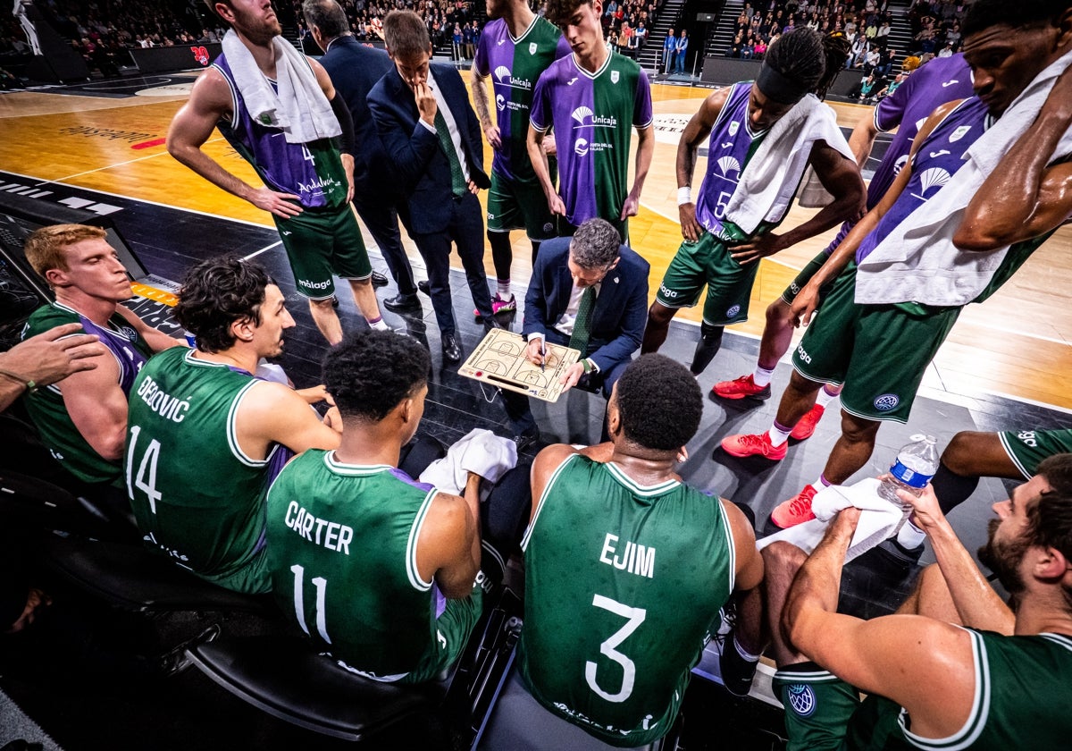 Los jugadores del Unicaja se saludan en un tiempo muerto alrededor de Ibon Navarro.