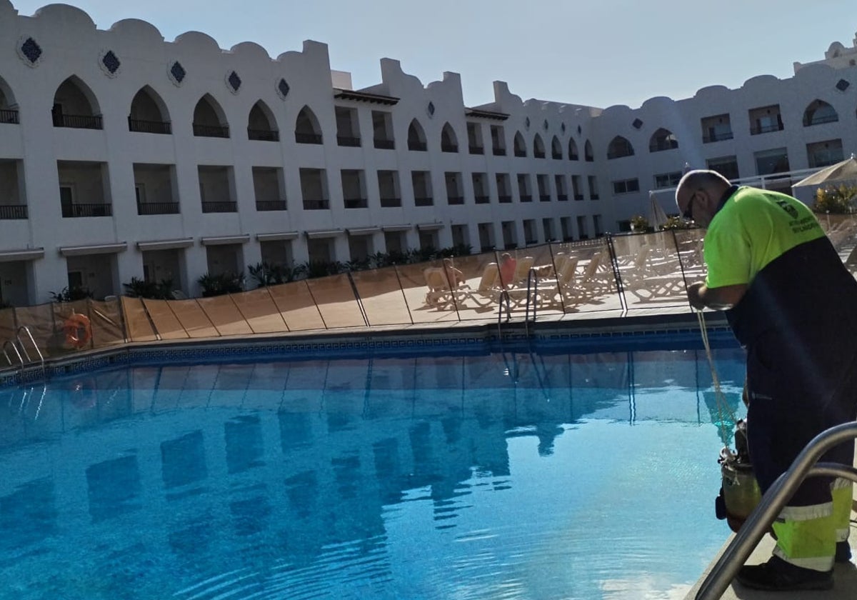 Un operario del Ayuntamiento de Benalmádena recoge el agua de la piscina de un hotel, donada para el riego.