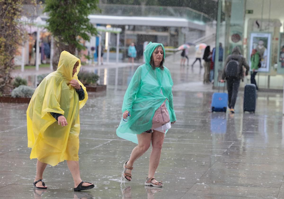 Dos mujeres con chubasqueros este lunes en Muelle Uno.