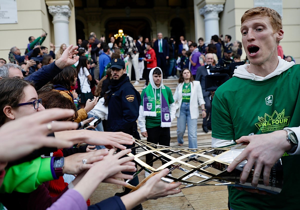 Alberto Díaz deja que un grupo de aficionados toque el trofeo de la Champions.