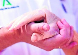 Un médico coge la mano de un paciente en cuidados paliativos. SUR