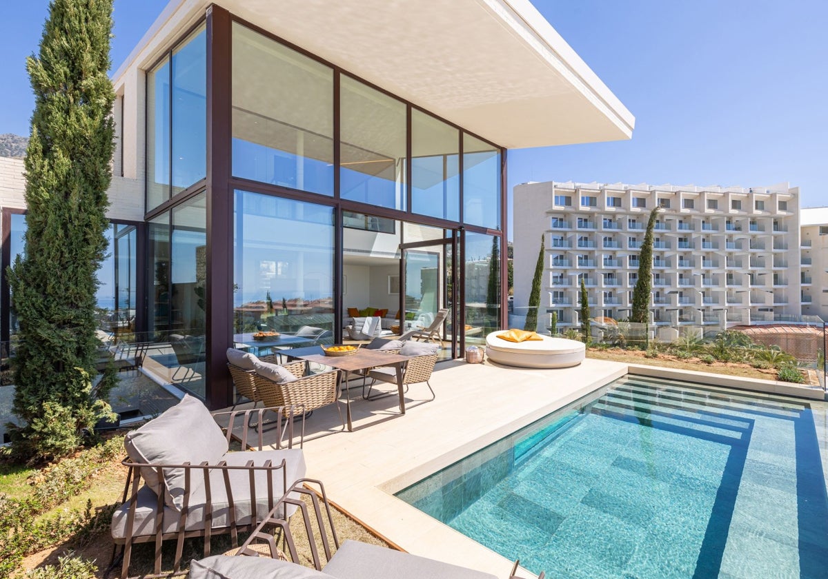 Vista de la terraza y la piscina de una de las villas, con el edificio de apartamentos al fondo.