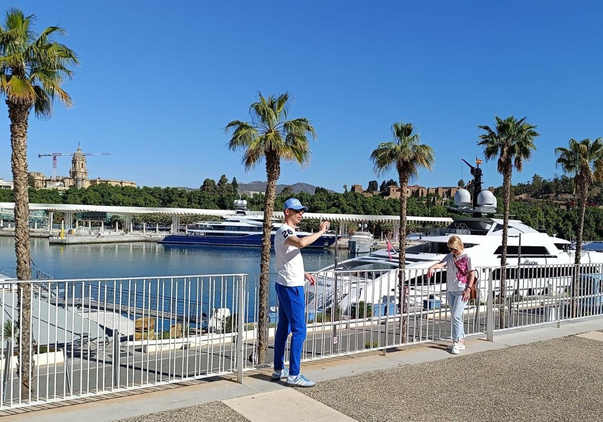 Turistas se hacen fotos con los megayates amarrados en el puerto de Málaga.