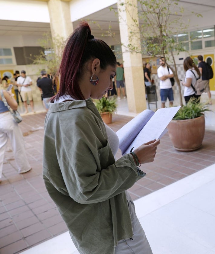 Imagen secundaria 2 - La presidenta del tribunal, Ana Belén Villena, lee a los opositores las instrucciones a seguir. Candidatos, en uno de los patios de la Facultad de Derecho, donde una joven da un último repaso a los apuntes. 