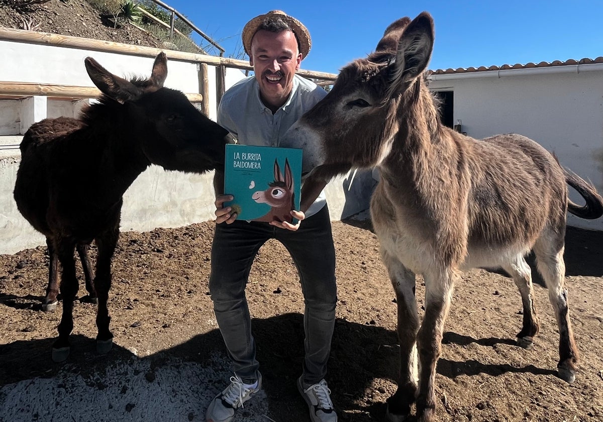 El escritor y guía turístico de El Borge, en su finca, junto a sus burras Ruperta y Baldomera, con un ejemplar de su primer libro.