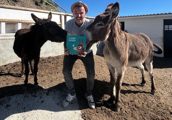 El escritor y guía turístico de El Borge, en su finca, junto a sus burras Ruperta y Baldomera, con un ejemplar de su primer libro.