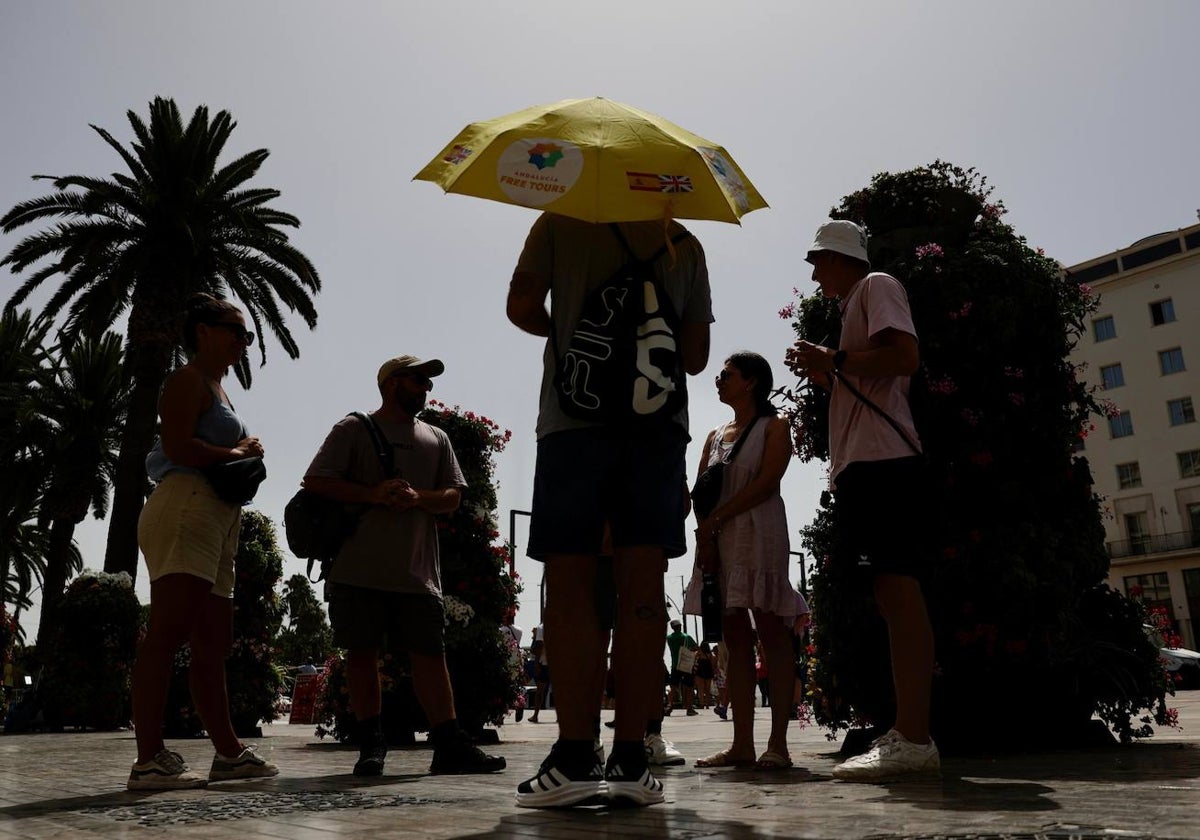 Turistas protegidos del sol con gorras y paraguas.