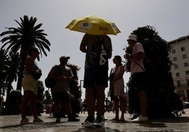 Turistas protegidos del sol con gorras y paraguas.