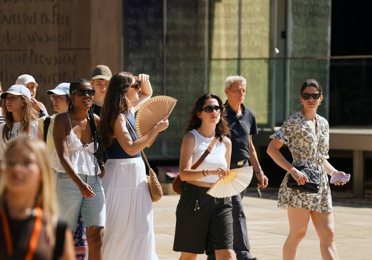 Turistas pasean por la calle Alcazabilla armadas con abanicos.