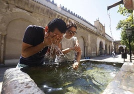 Unos turistas se refrescan en una fuente de Córdoba