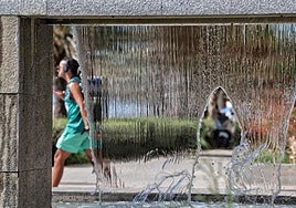 Un turista camina junto a una fuente en la capital malagueña.