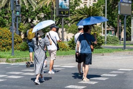 Imágenes de personas al lado de un termómetro en las calles de la capital hispalense a 47 grados de temperatura