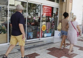 Viandantes pasan frente al escaparate de un comercio en Torremolinos.