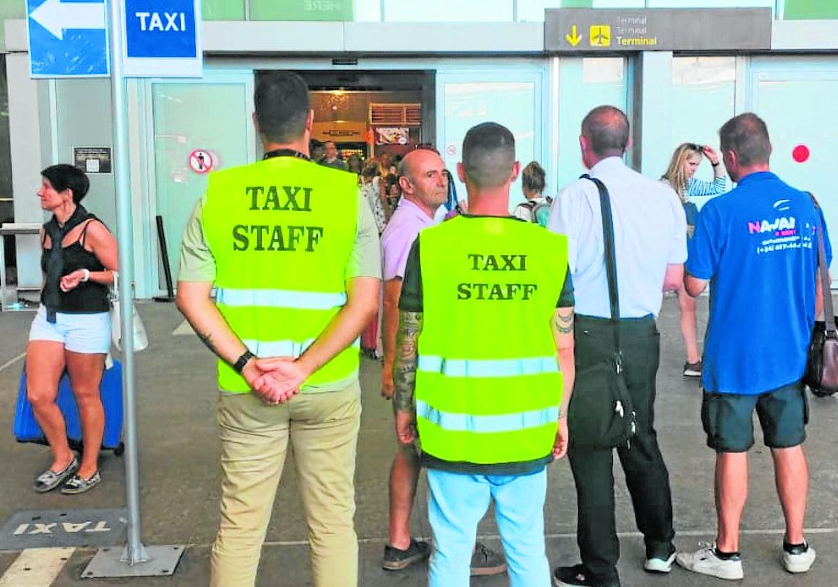 Dos taxistas vigilan que la terminal de salidas para impedir que los piratas capten a turistas.