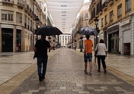 Personas caminan por una casi desierta calle Larios en un reciente día de lluvia.