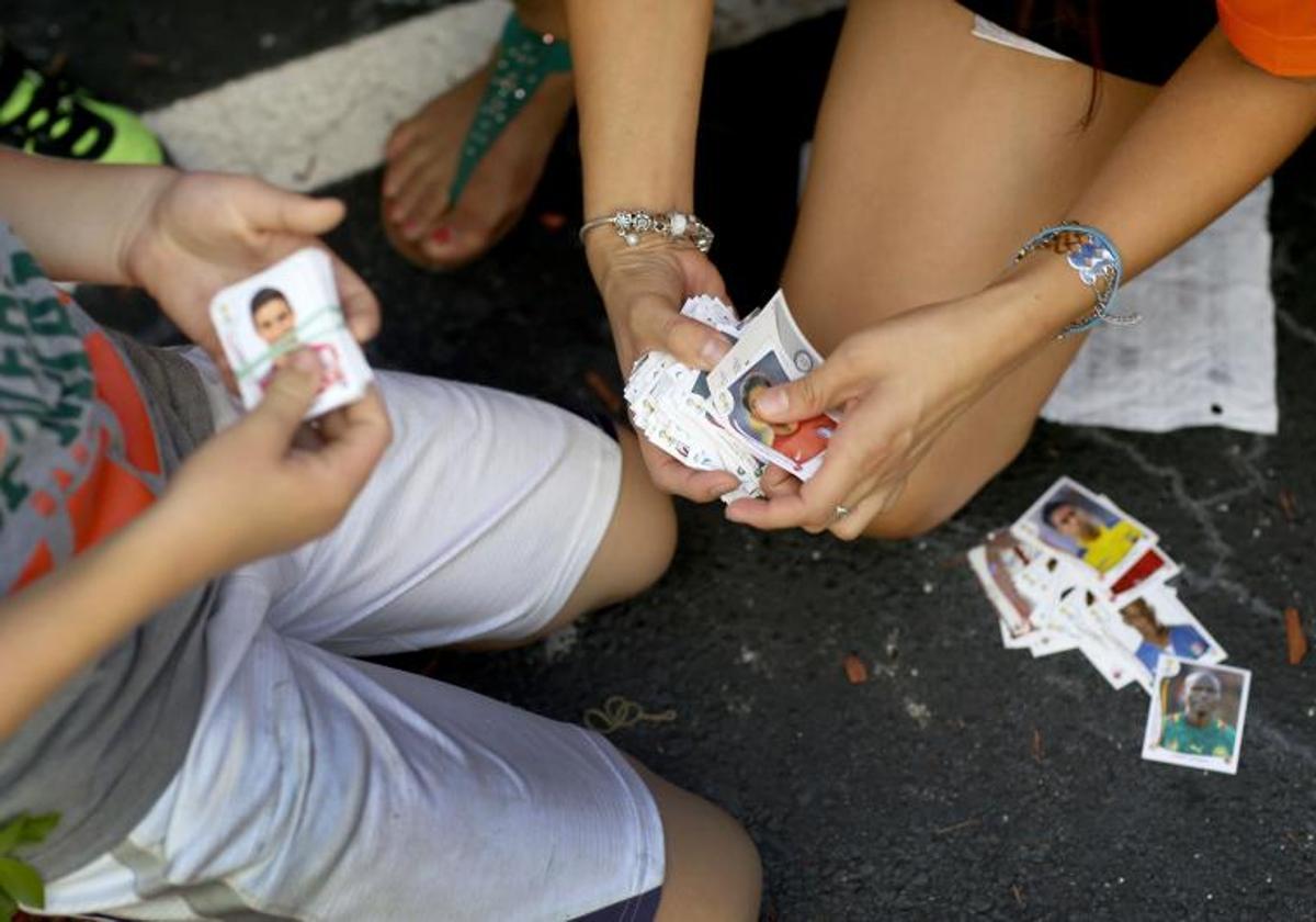 Varios niños se intercambian cromos de fútbol.