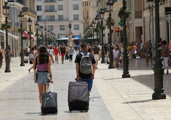 Turistas caminan por el Centro de Málaga hacia su alojamiento.