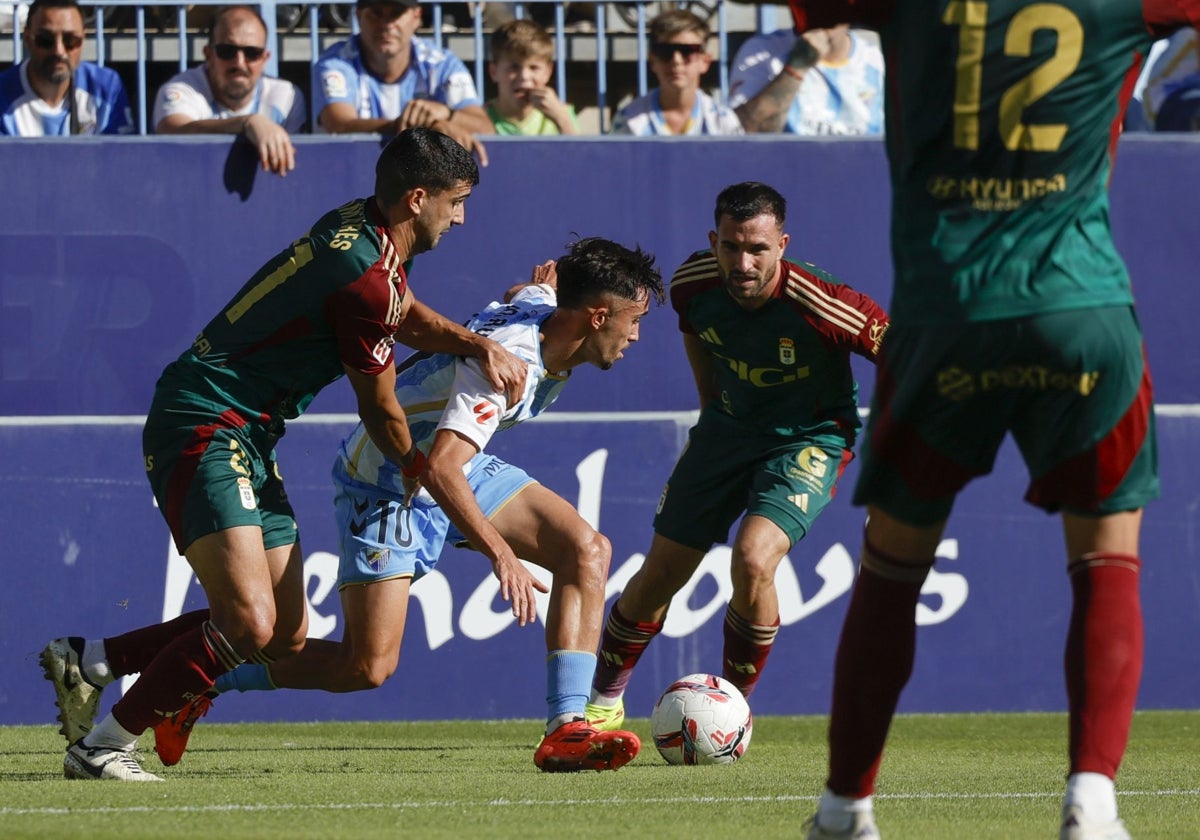 Larrubia, uno de los cinco malagueños en el once inicial, caracolea entre Pomares y Moyano en una acción en la que cayó en el área y acabó reclamando penalti.