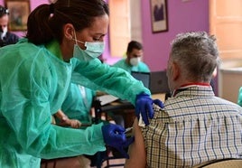 Una profesional de enfermería pone una vacuna de la gripe a un ciudadano.