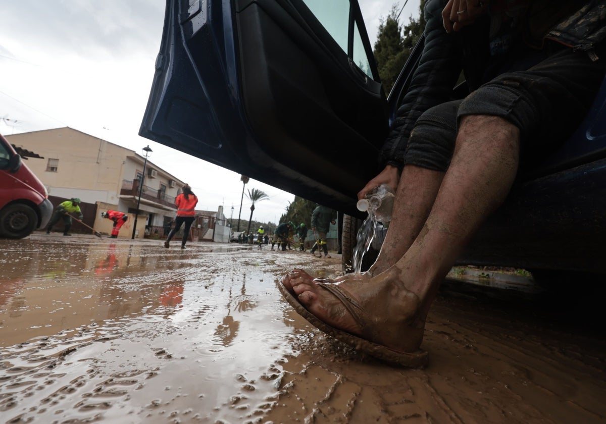 Un afectado por las inundaciones se limpia el barro de los pies.