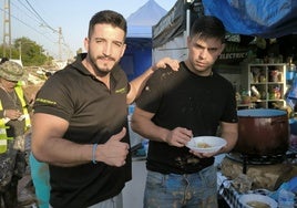 Álvaro Faura, de 30 años, a la izquierda, en la carpa instalada por él en Paiporta para cocinar a los vecinos.