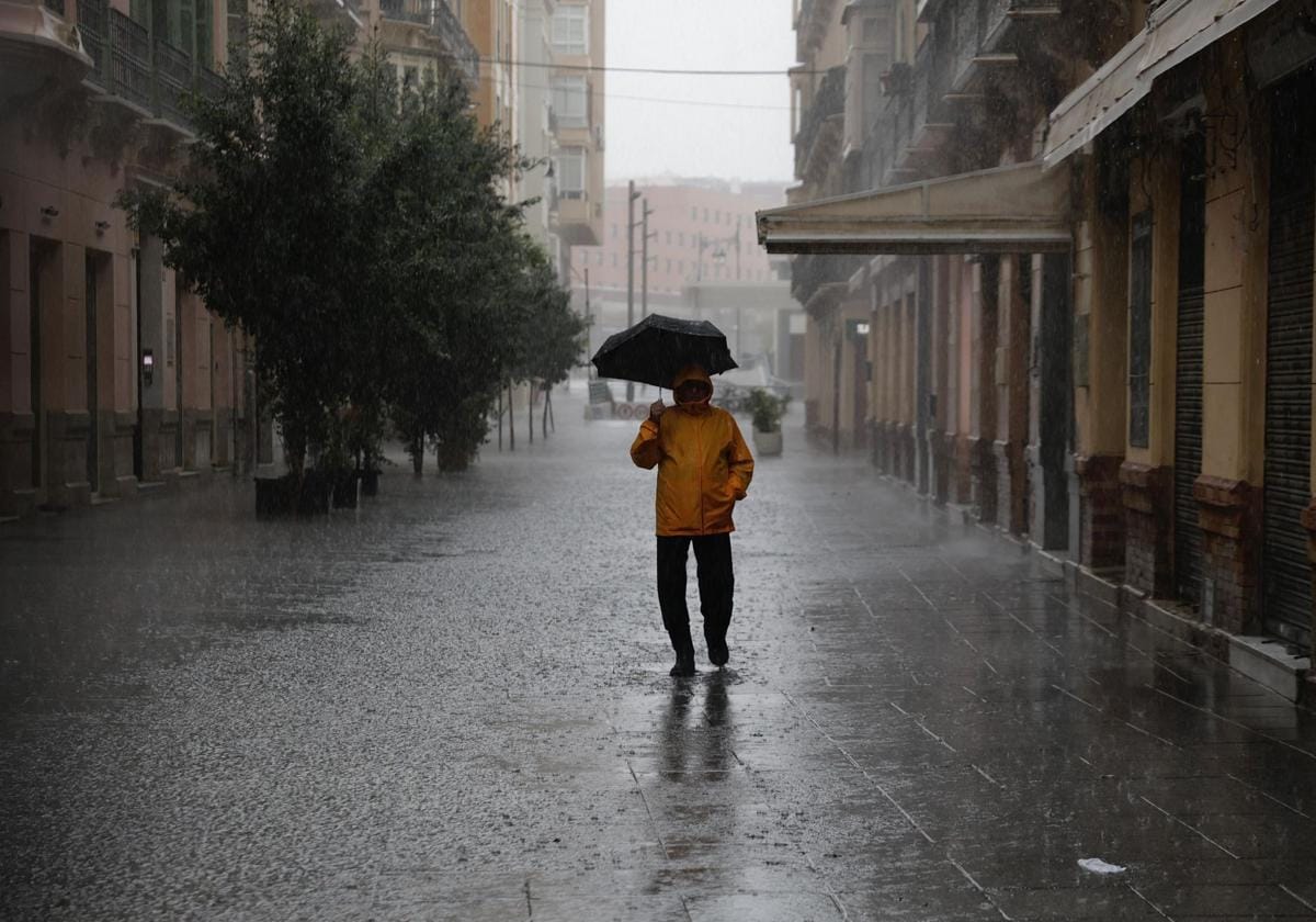 Un hombre camina en soledad bajo la lluvia por una calle de Málaga este miércoles.