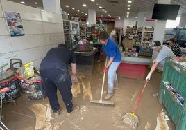 Los empleados del supermercado Covirán de Benamargosa, este jueves limpiando el barro.