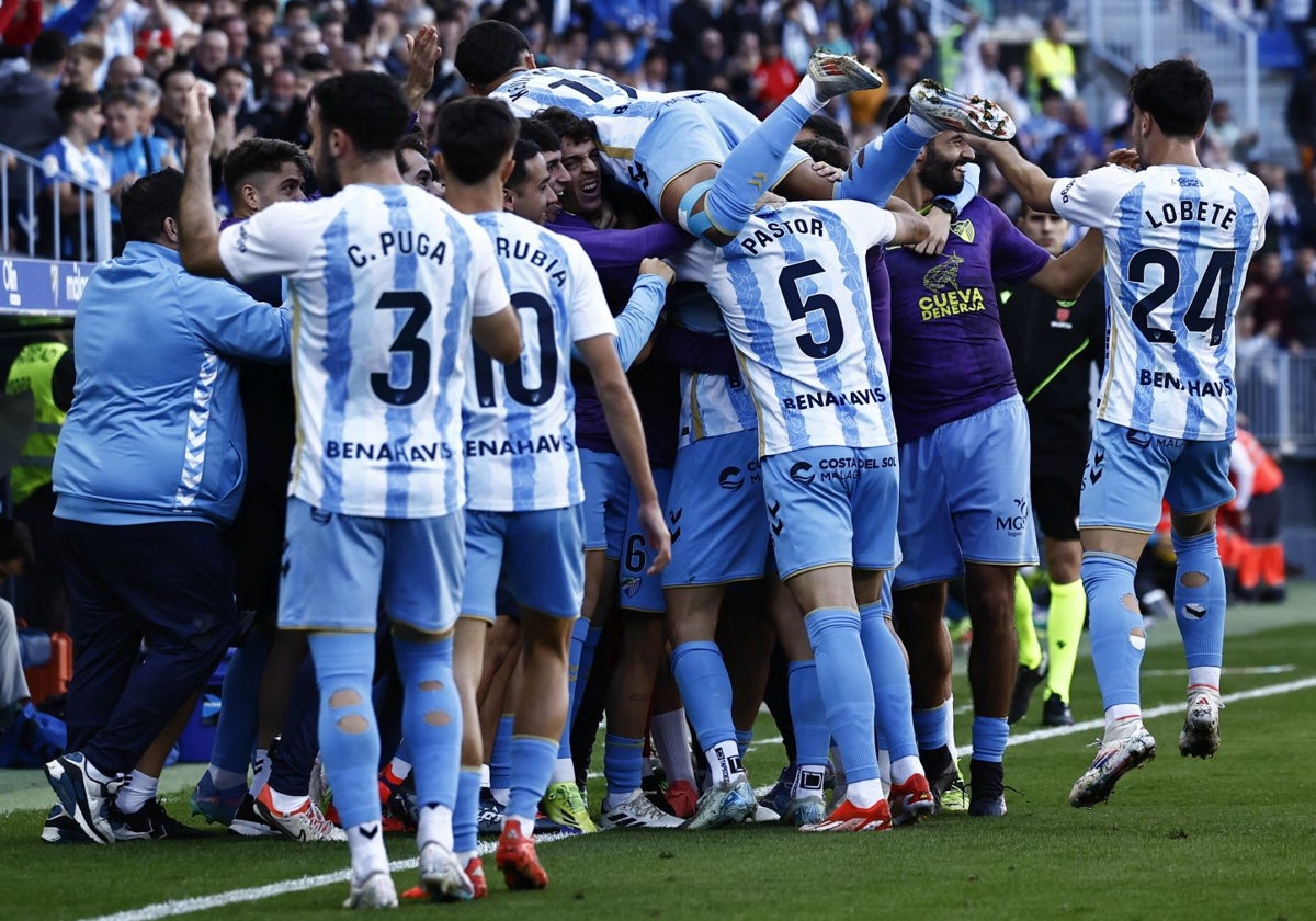 Los jugadores celebran con el banquillo el último gol del Málaga, el de Dioni.