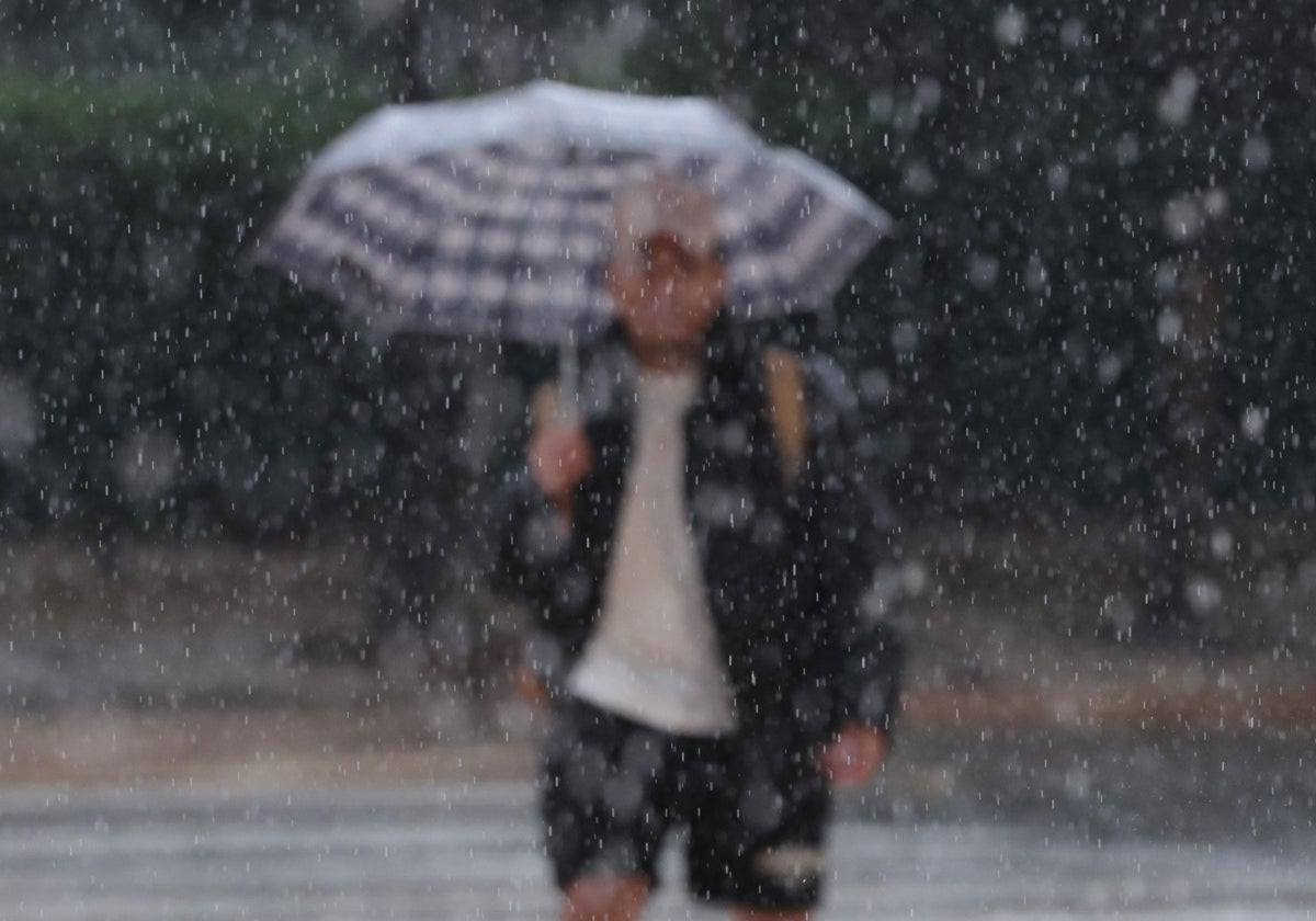 Un turista pasea bajo la lluvia en Málaga.