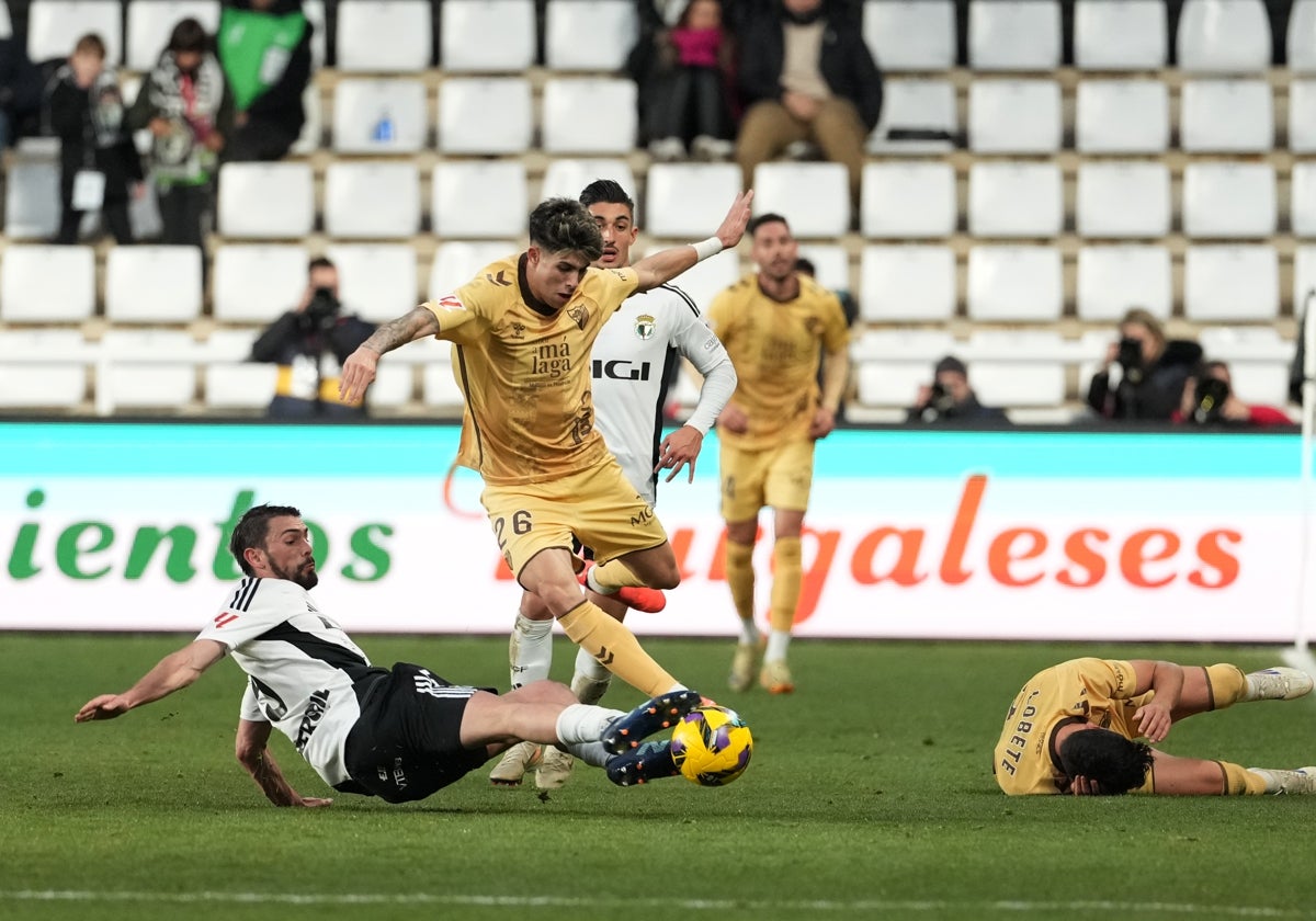 Antoñito intenta esquivar la entrada del jugador del Burgos, con Julen Lobete tendido en el suelo.