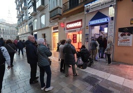 Clientes ante la administración El Gato Negro en el Centro de Málaga.