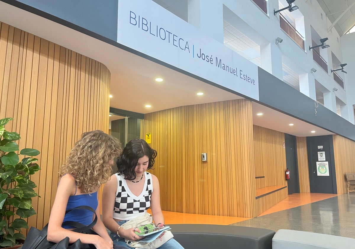 Alumnas frente a la biblioteca de la Facultad de Educación atentas a un iPad.