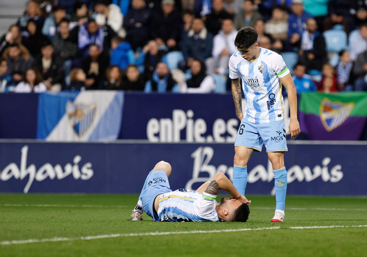 Dioni, tendido en el suelo tras un golpe en el choque frente al Levante, acompañado de Antoñito.