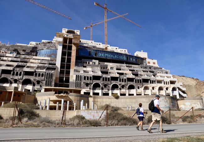 Así está el hotel. Dos paseantes circulan frente a la mole, con la estructura al 95% cuando se paralizaron los trabajos