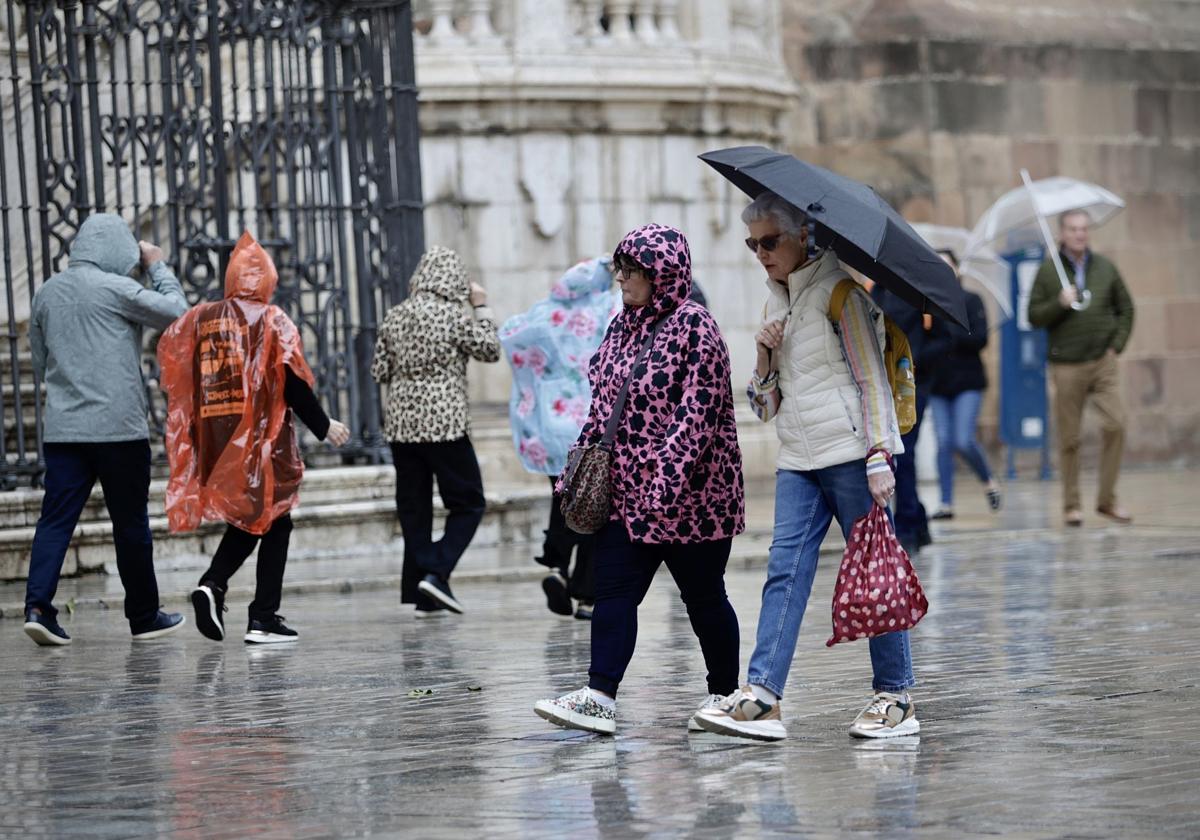 Turistas paseando por Málaga bajo la lluvia.