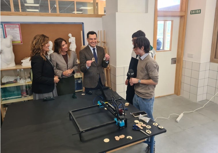 El presidente de la Junta muestra las insignias elaboradas por los alumnos en el taller del centro.