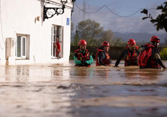 Bomberos con el agua por la cintura en la barriada Doña Ana de Cártama.