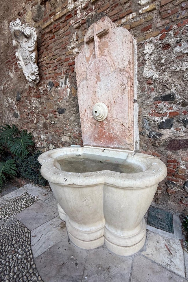 La fuente de la entrada, restaurada, pero sin funcionamiento y con el agua estancada.