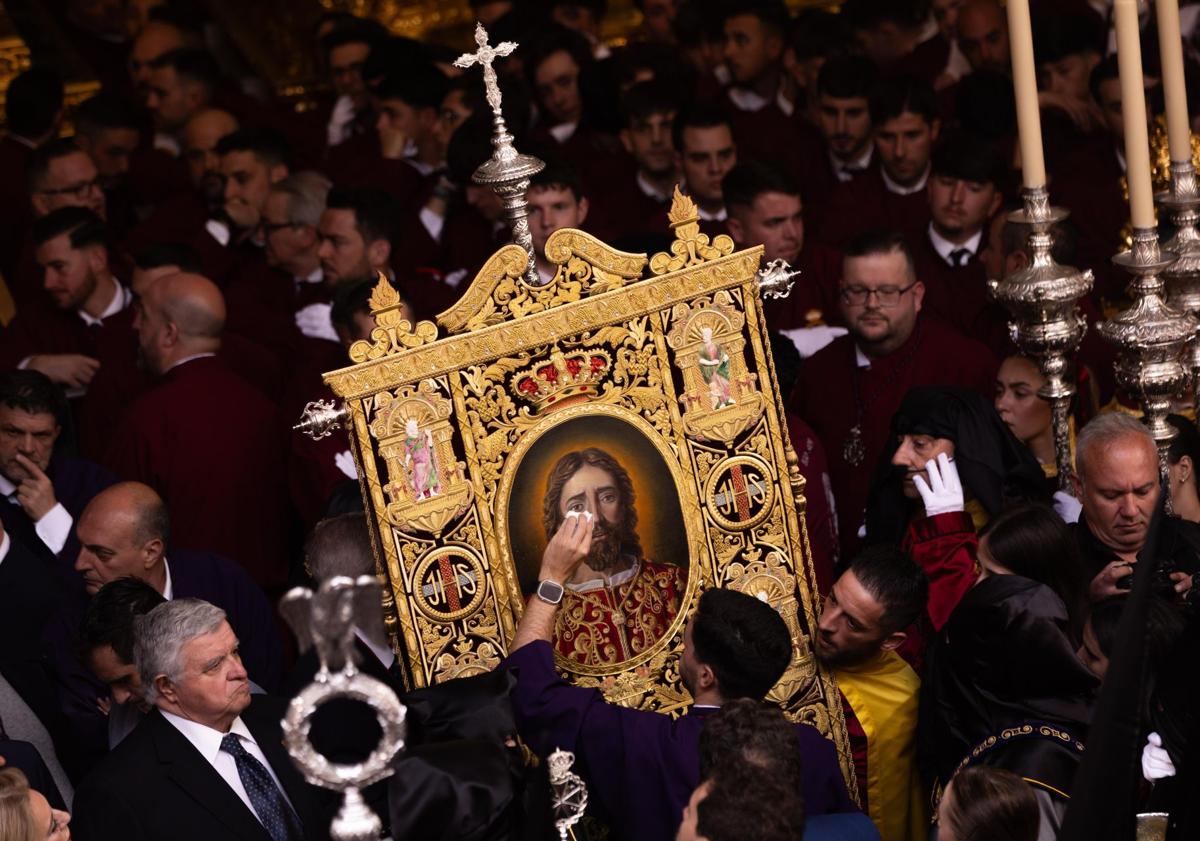 Imagen principal - 1. Miembros de la cofradía del Rescate limpian un estandarte tras la lluvia caída. 2. Espectadores en las sillas con paraguas. El Cristo de la Agonía (Penas) tuvo que recogerse nada más salir. 