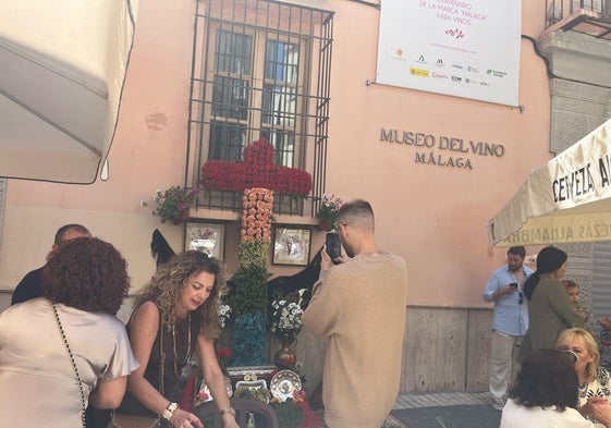 Un hombre fotografía la cruz adornada con flores en la plaza de Viñeros.