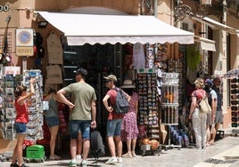 Turistas buscan un recuerdo de la ciudad en un comercio del Centro de Málaga.