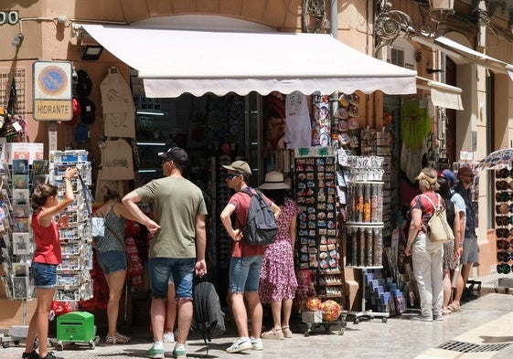Turistas buscan un recuerdo de la ciudad en un comercio del Centro de Málaga.