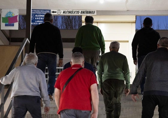 Varias personas suben las escaleras para entrar en la pequeña sala de reunión de Alcohólicos Anónimos.