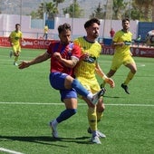 'Gato', jugador del Torre del Mar, golpea el balón incomodado por un jugador del Huétor Tájar.
