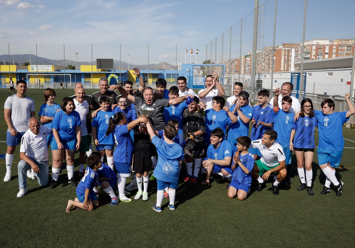 Los niños de Espíritu Deportivo y algunas leyendas del Málaga levantan el trofeo conmemorativo en el campo de la Unión Deportiva Dos Hermanas-San Andrés.