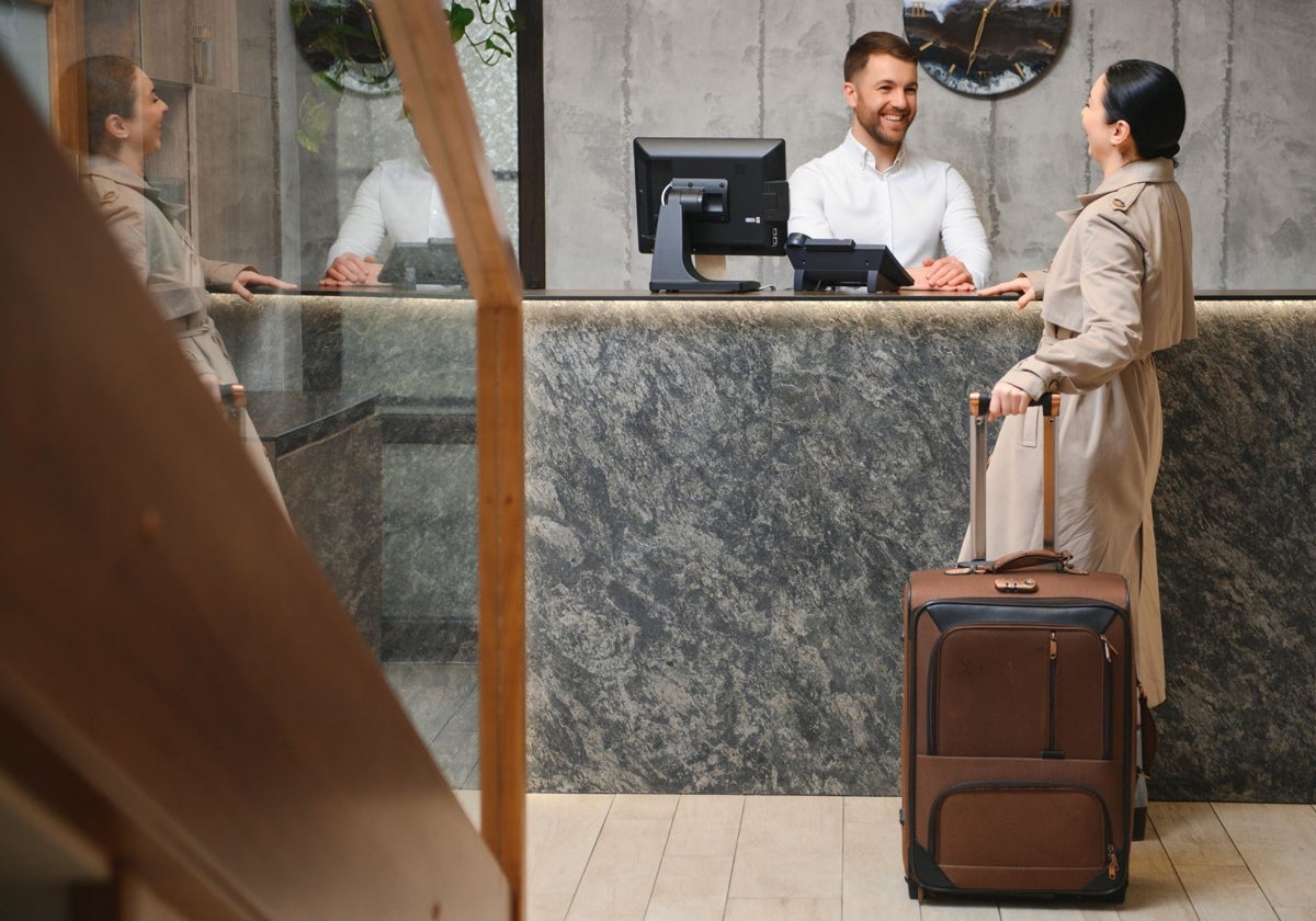 Recepcionista de un hotel atiende a una turista.