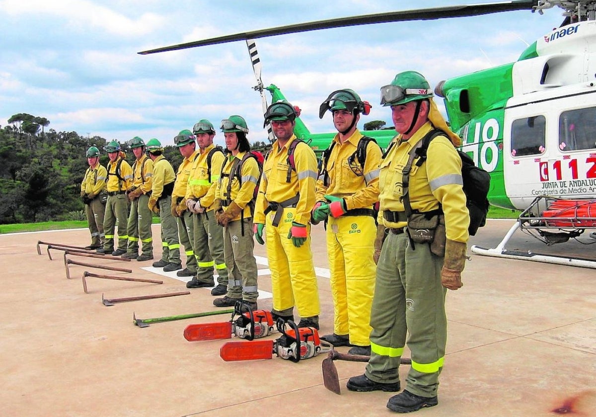 Operativos del Plan Infoca, delante de un helicóptero utilizado para la extinción.